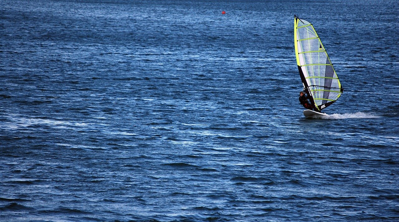 Windsurfen und Kitesurfen am Forggensee - mit Neuschwanstein im Vordergrund und der Landzunge am Campingplatz Brunnen im Hintergrund